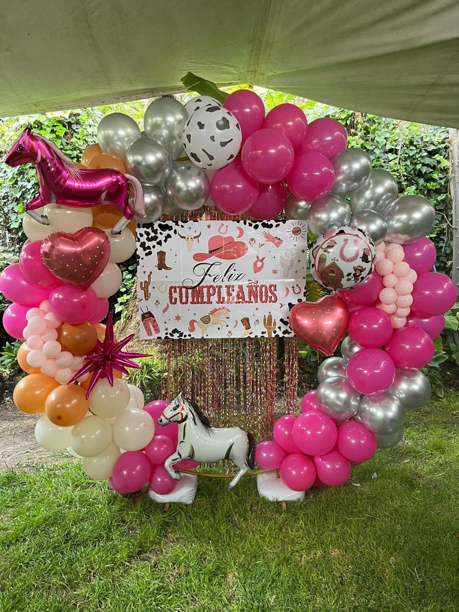 Aro 360 cubierto de globos rosas, plateados y crema en un jardín