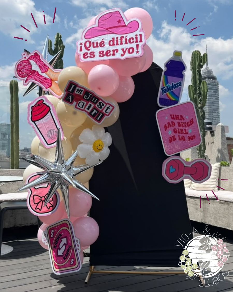 Mampara 180° con fondo de tela negra, guirnalda orgánica de globos rosa y crema, estrella metálica y figuras temáticas en coroplast, en una terraza